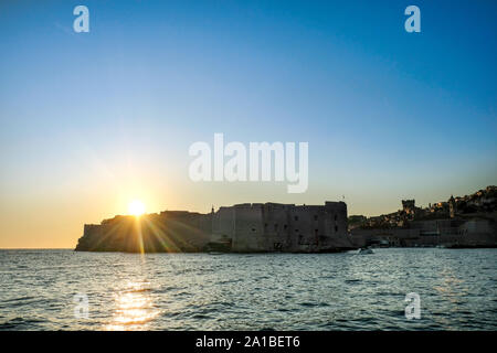 A view from a boat as it approaches Dubrovnik Old Town harbour, or old port,  just as the sun  sets over the famous Old Town historic walls Stock Photo