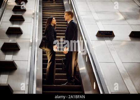Two business colleagues riding an escalator together. Stock Photo
