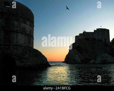 A view out to the Adriatic sea from the Old Town of Dubrovnik at sunset. The view shows the city walls with Alpine Swifts in flight in the sky Stock Photo