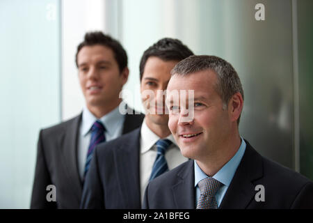 Three businessmen standing in a line together. Stock Photo