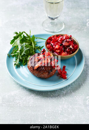 Grilled Burger with Tomato and Pepper Salsa, Rocket and White Wine. Stock Photo