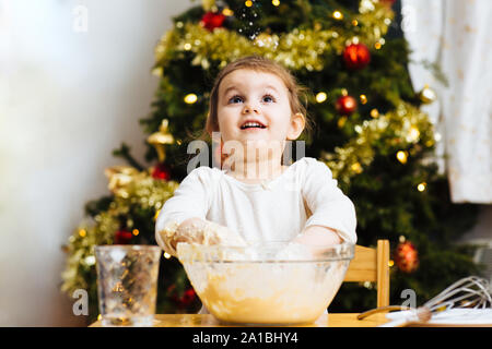 Little girl making food and looking up dough Stock Photo