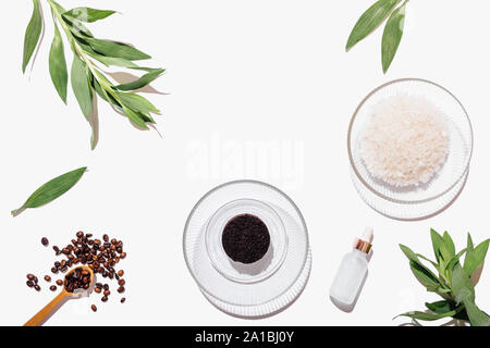 Glass bowl with tablet of ground coffee next to sea salt and bottle of cosmetic oil ingredients for homemade natural body scrub on white background, f Stock Photo