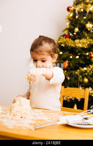 Toddler girl putting flower on dough for christmas cookies Stock Photo