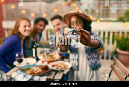 Group of diverse friends taking selfies pictures having dinner al fresco in urban setting Stock Photo