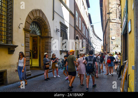 Street view of Via Fillungo, the main street of the historic centre of Lucca, with a crowd of young tourists in a sunny summer day, Tuscany, Italy Stock Photo