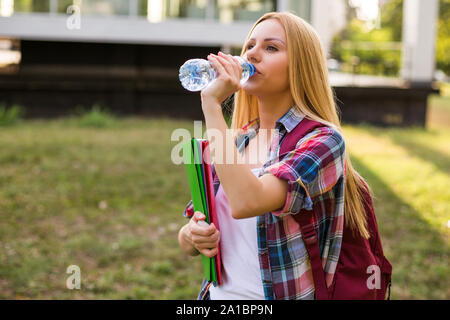 Female student drinking water while standing outdoor. Stock Photo