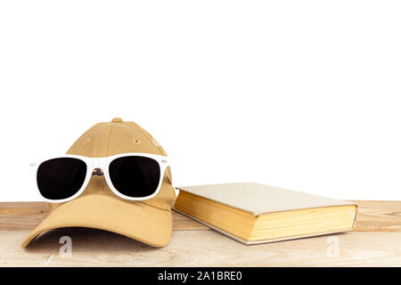Sunglasses, baseball cap, book, lie on wooden boards on a white background. Stock Photo