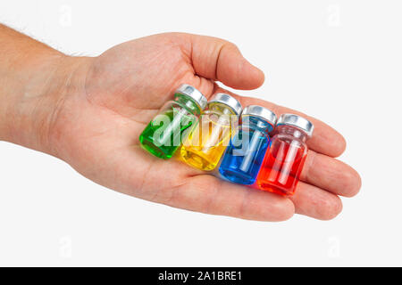 Hand holds glass jars of medicine, on white background. Stock Photo
