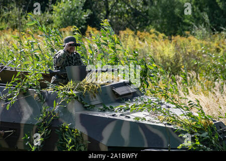 A German soldier observes (Sd.Kfz.251) the battlefield through binoculars during the military historical reconstruction of 'Karpaty 1944' in Medzilabo Stock Photo