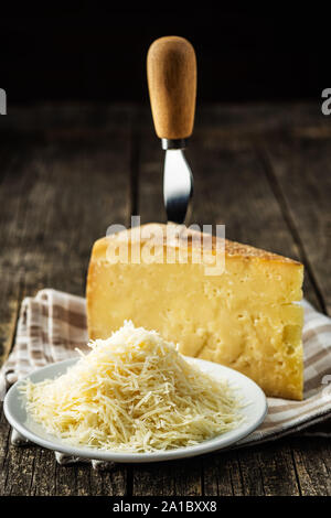Tasty grated cheese. Parmesan cheese on old wooden table. Stock Photo