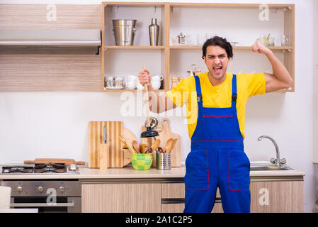 The young male contractor repairing tap at home Stock Photo