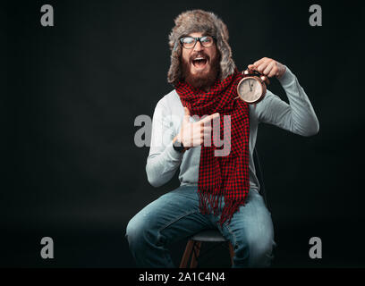 Portrait of amazed man with beard pointing at alarm clock Stock Photo