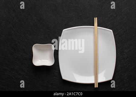 Empty white plate with chopsticks and a gravy boat on a dark background. Japanese food style. Top view with copy space Stock Photo
