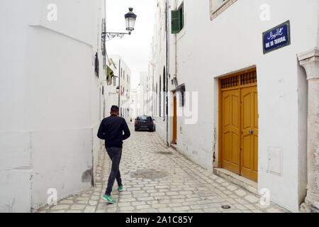 A young Tunisian man walking through the pedestrian streets of the Hafsia quarter of the medina (old city) of Tunis, Tunisia. Stock Photo