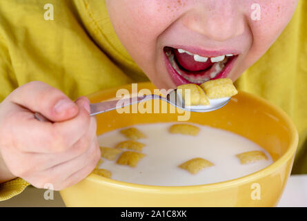 Teenage Boy Sitting at Kitchen Table at Home in Morning Eating Cereal for Breakfast Meal Stock Photo