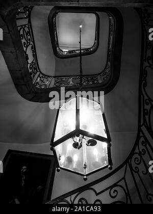 Ancient spiral staircase in old house with big lamp connected on long metal chain, France Stock Photo