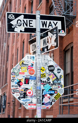 The back of a stop sign covered in stickers, graffiti and tags. On Washington and Front streets in the Dumbo section of Brooklyn, New York. Stock Photo