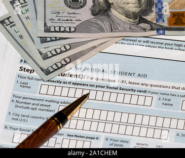 Student financial aid application form for college tuition loans and grants with one-hundred dollar bills and ballpoint pen Stock Photo