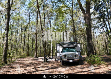 A large Class C RV caravan with slides is seen at the campground at Ichetucknee Springs State Park in Florida, a beautiful area off the beaten path. Stock Photo