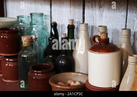 A shelve with different glass bottles, ceramic mugs, and bowls at Fort Nisqually in Tacoma, Washington Stock Photo