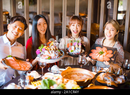 young friends showing seafood  beef and pork slices  in hot pot restaurant Stock Photo