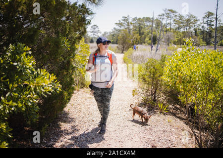 Mid aged woman is hiking on the trail with her dog Stock Photo