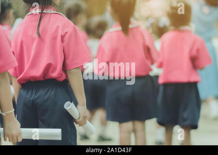 Back view of little girls use paper rolls instead of long cheerleader Baton Sticks for school parade marching practice. Stock Photo