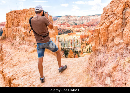 Man tourist person standing taking picture of view with camera at Queens Garden Navajo Loop trail at Bryce Canyon National Park in Utah Stock Photo