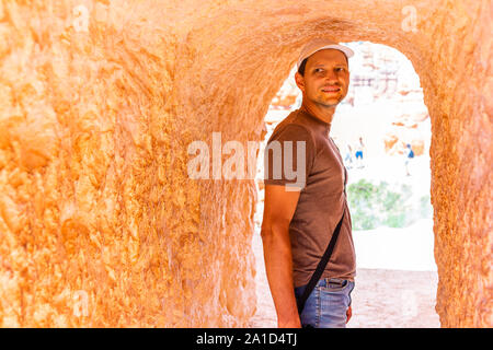 Man tourist person standing in tunnel with orange color at Queens Garden Navajo Loop trail at Bryce Canyon National Park in Utah Stock Photo