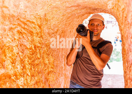 Man tourist person taking picture in tunnel with orange color at Queens Garden Navajo Loop trail at Bryce Canyon National Park in Utah Stock Photo
