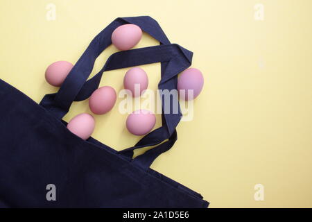 Black reusable shopping bag with eggs against the yellow background Stock Photo