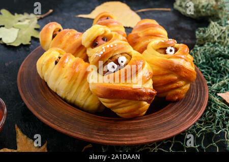 Funny sausage and cutlets mummies in dough with eyes, ketchup on table. Halloween food. Stock Photo