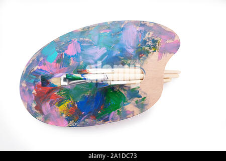 Wooden palette with paints and brushes isolated on white background Stock Photo