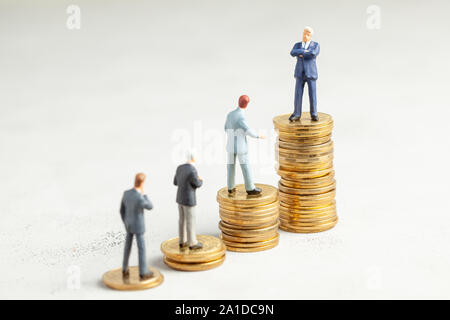 Successful businessman with big profits at the top of the stairs by coins and less successful businessmen with small companies. Adequate investment in the company Stock Photo