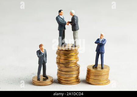 Businessmen shake hands as a symbol of a successful profitable transaction. Businessmen on a stack of gold coins as a symbol of success or successful investments. Stock Photo