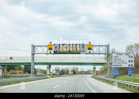 Illinois highway, USA. May 8, 2019: Warning road sign billboard for stopped vehicles and speed limits on a highway, cloudy sky Stock Photo