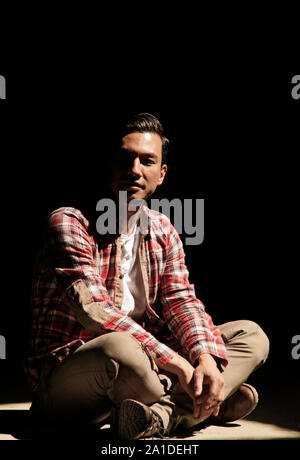 Handsome man with dark hair sitting in a beam of light Stock Photo