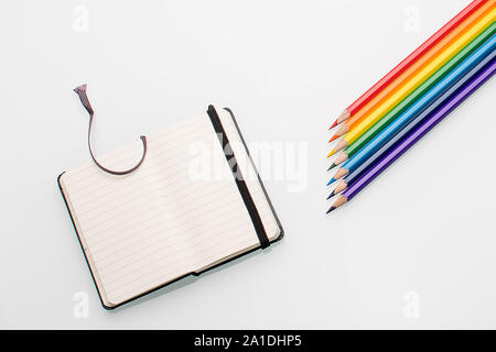 Clean notepad and rainbow color pencils in the shape of an arrow on a white background top view Stock Photo