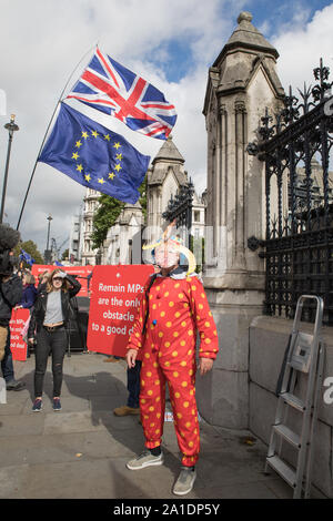 Westminster, London, UK. 25 September 2019. Remain and leave protesters demonstrate outside the House of Parliament.  A man wears a clown outfit resembling Boris Johnson. MPs return to Parliament the day after the Supreme Court declared that Boris Johnson proroguing of Parliament was unlawful.  MPs debate in the House the outcome of the Supreme Court decision and the Prime Minister Boris Johnson faces questions from MPs. Stock Photo