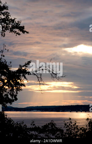 The setting sun filters through the clouds as seen from Mackinac Island, Michigan. Stock Photo