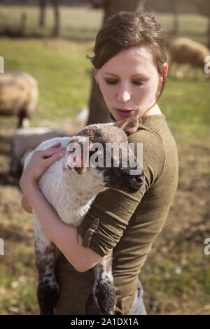 young woman holding a cute lamb, concept affectionate breeding and care Stock Photo