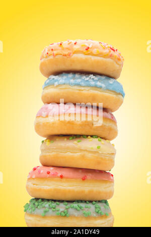 Tower of colored donuts, pastries with yellow background. Stock Photo