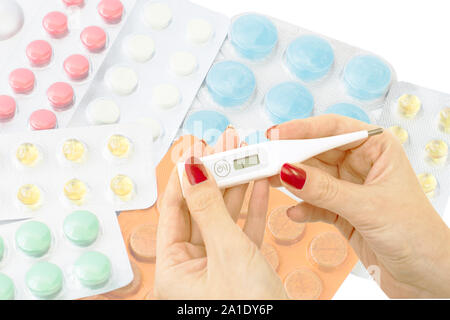 Electronic thermometer in the hands of doctors against the backdrop of various tablets for the treatment of patients Stock Photo