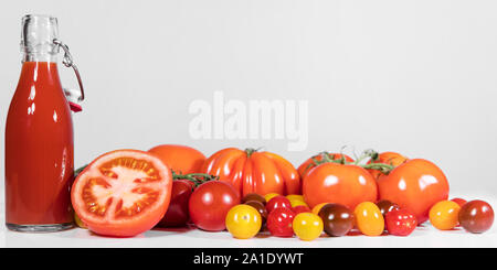 panorama with various tomatoes and a bottle  in front of a white and grey background Stock Photo