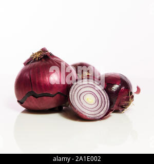 red onions, unpeeled and sliced in front of white Stock Photo