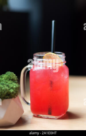 Pink cocktail with lemon and black straw, cold drink in cafe. Refreshing lemonade with empty space for text or menu. Selective focus Stock Photo