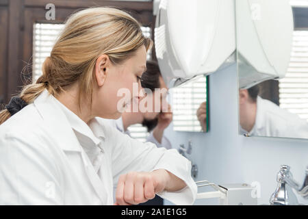 medicine staff in hospital is desinfecting the hands, having a conversation Stock Photo