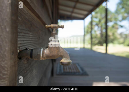 An outside brass tap or faucet attached to a wooden timber house in Australia Stock Photo