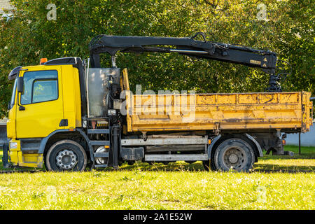 Yellow flatbed truck with crane arm Stock Photo